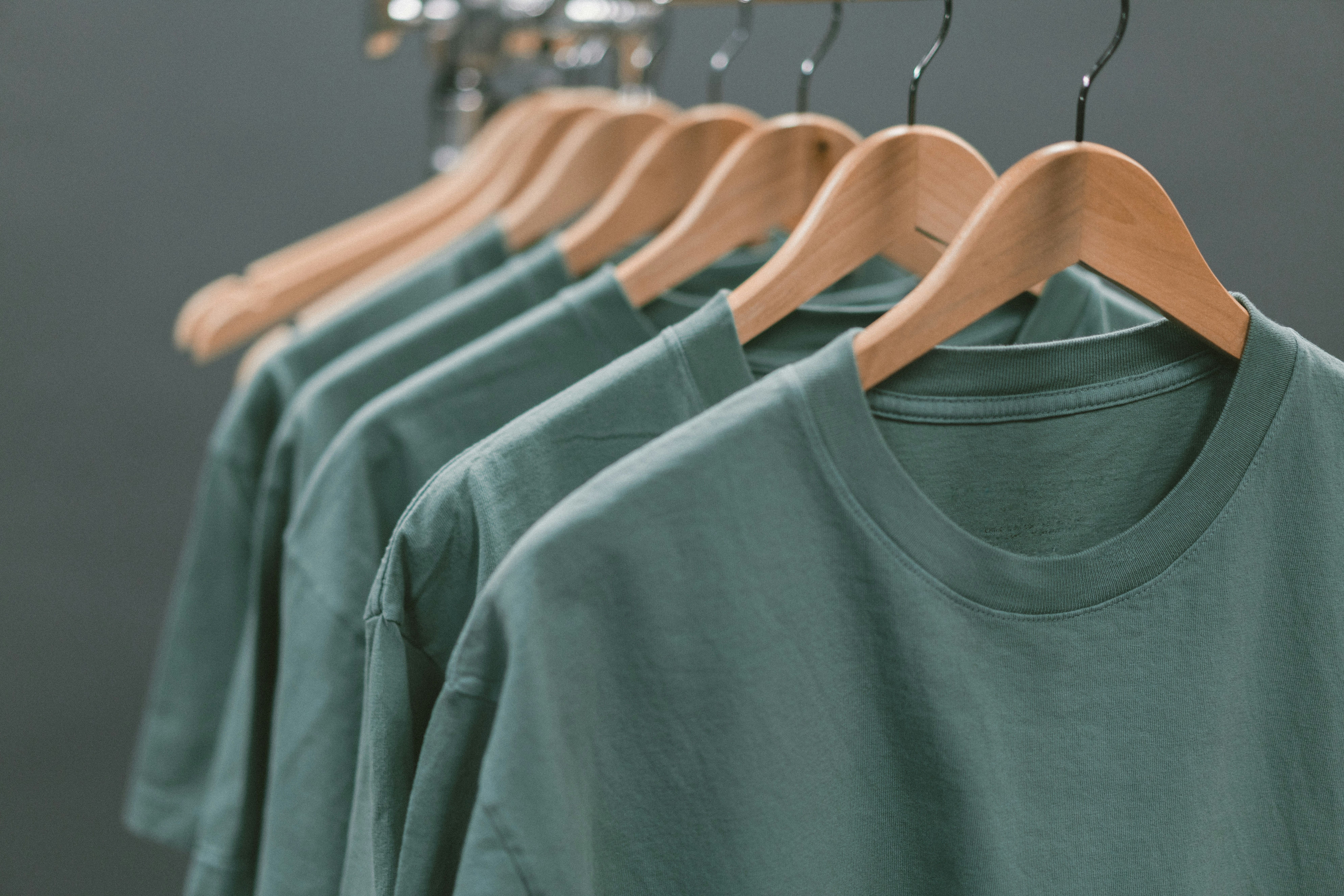 Camisetas pesadas color salvia colgadas en un perchero
