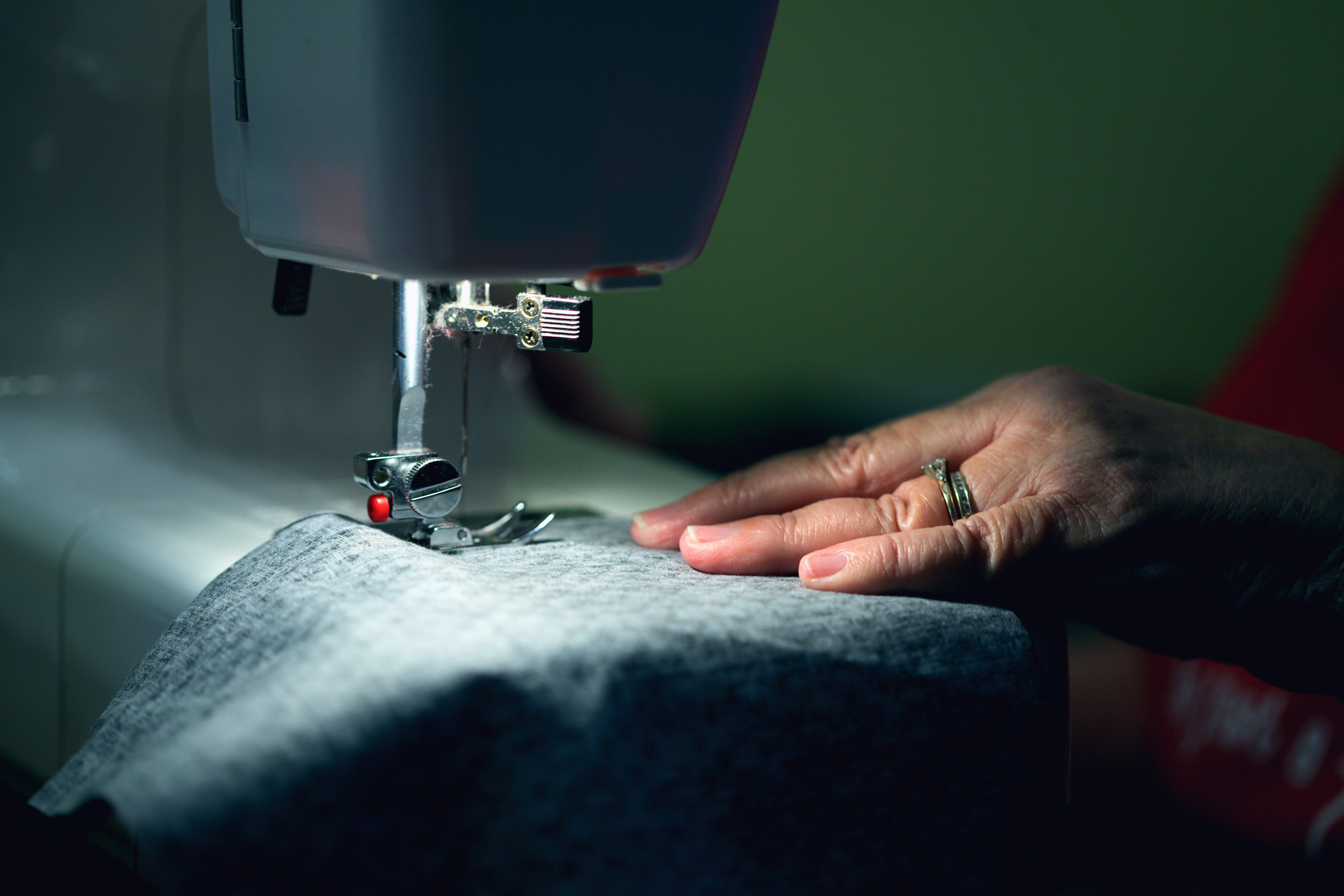Manos cosiendo una prenda en una máquina de coser